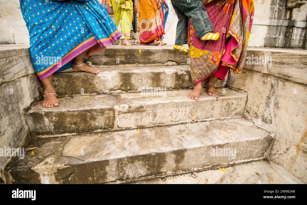 Le donne con sari e caviglia bracciali camminare a piedi nudi su ben usurati gradini in marmo tempio Jain, Ranakpur, India Foto Stock