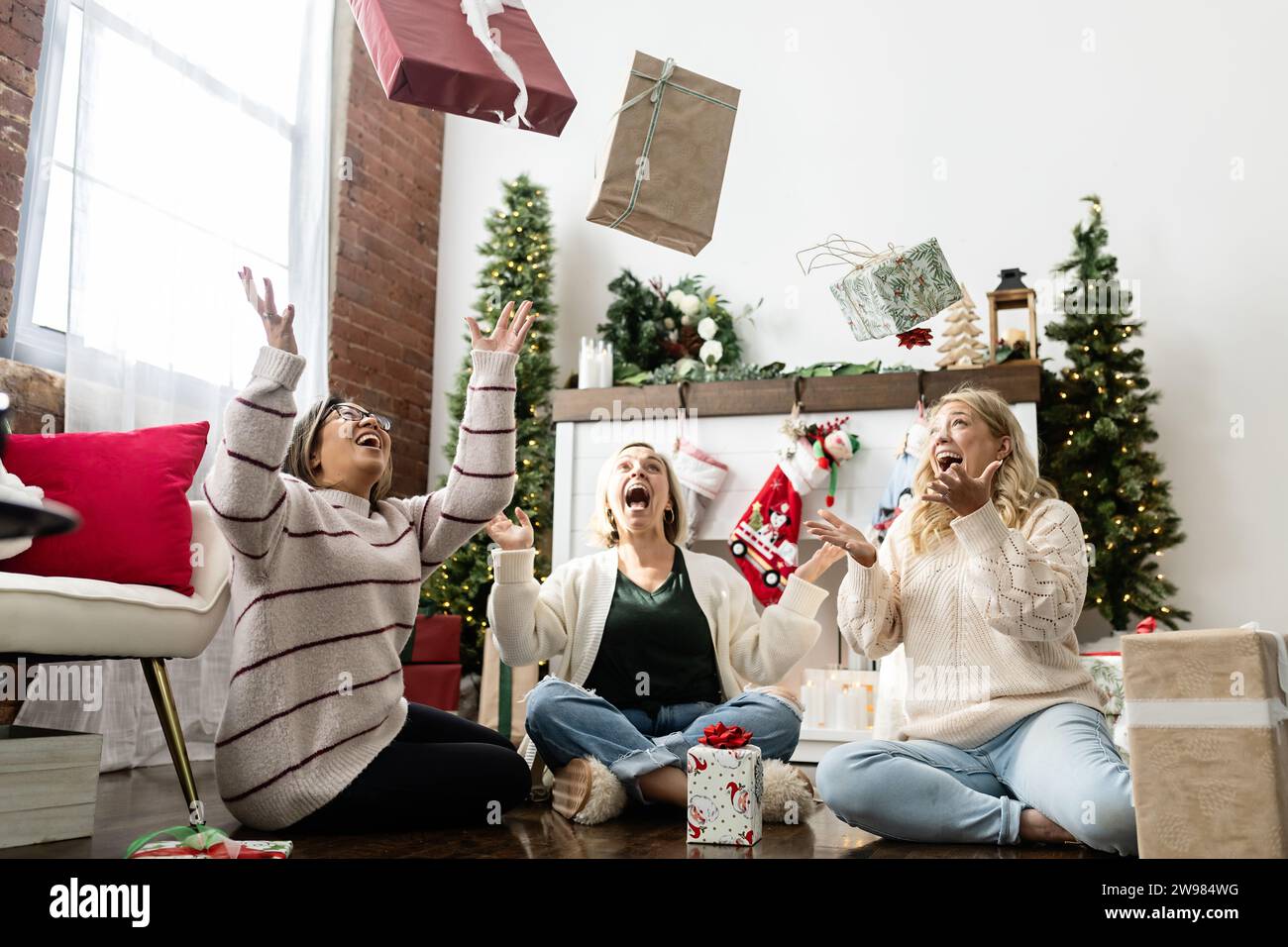 Donne che lanciano in aria regali di natale avvolti Foto Stock