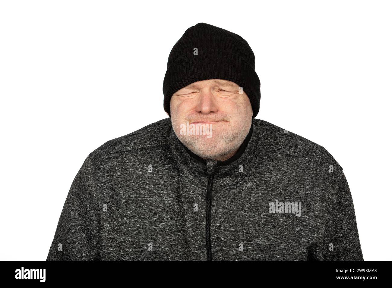 Chilly Caucasian Worker in Black Winter Hat si sente congelato su sfondo bianco Foto Stock