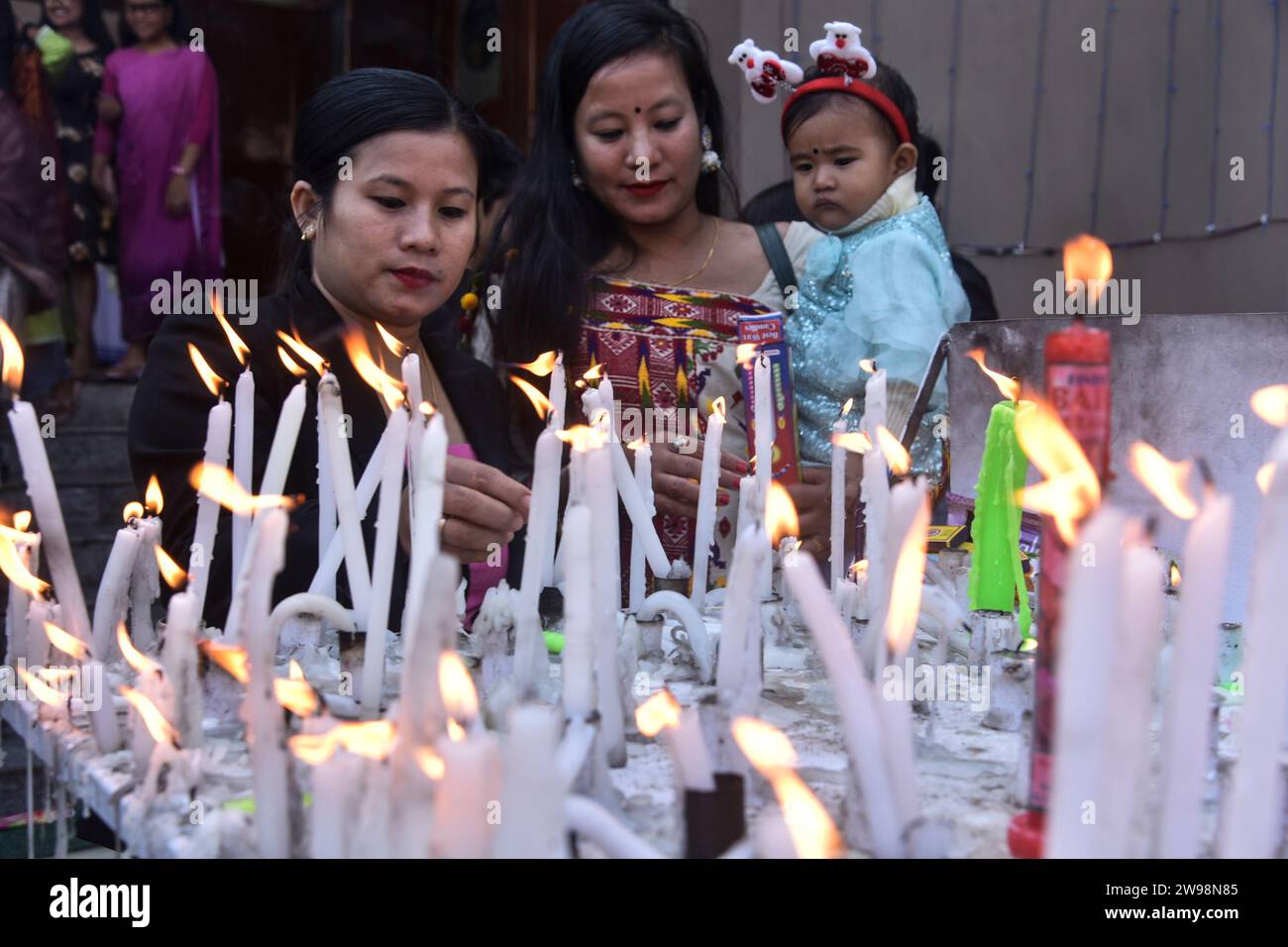 GUWAHATI, INDIA- DICEMBRE 25: I devoti accedono la candela in occasione della celebrazione di Natale, nella chiesa cattolica Dispur della cattedrale di Guwahati, India, il 25 dicembre 2023. Foto Stock