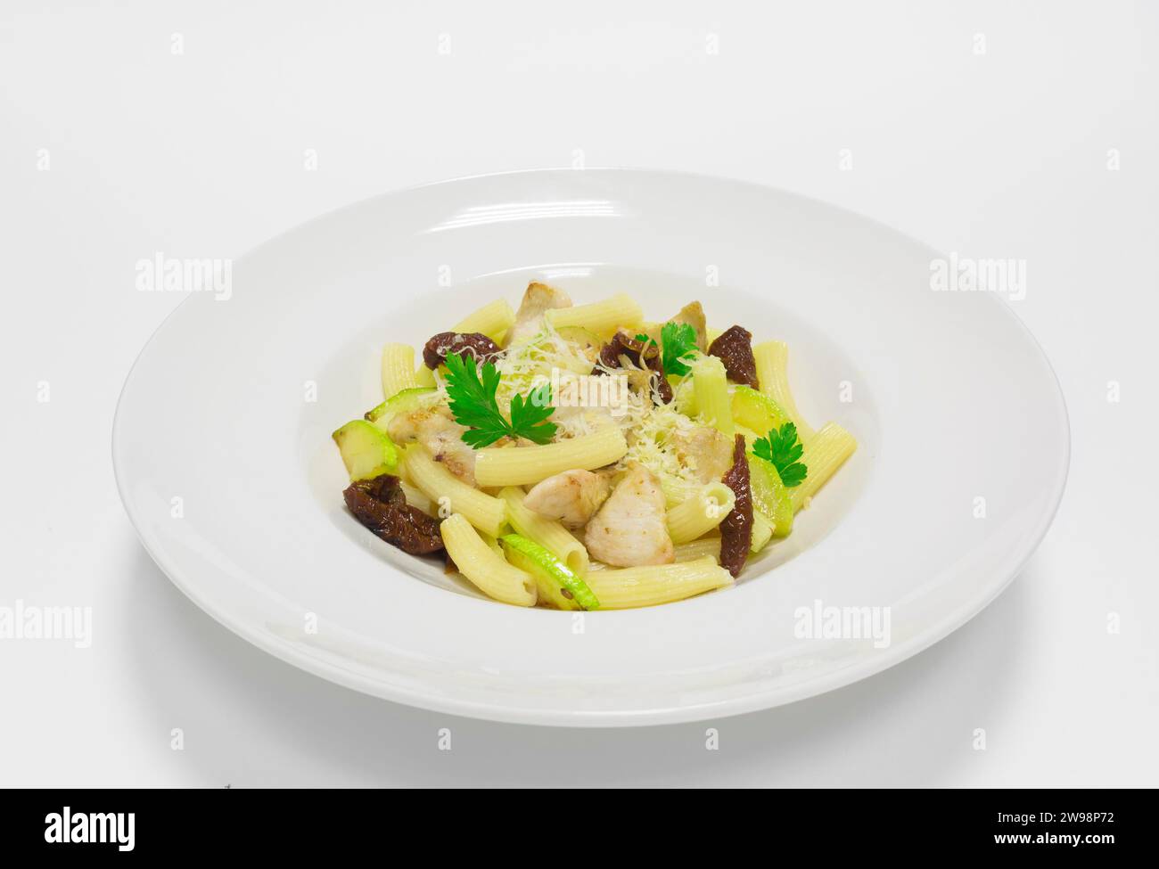 Pasta gourmet con maiale, zucchine e pomodori secchi. Vista dall'alto. Sfondo bianco. Supporti misti Foto Stock