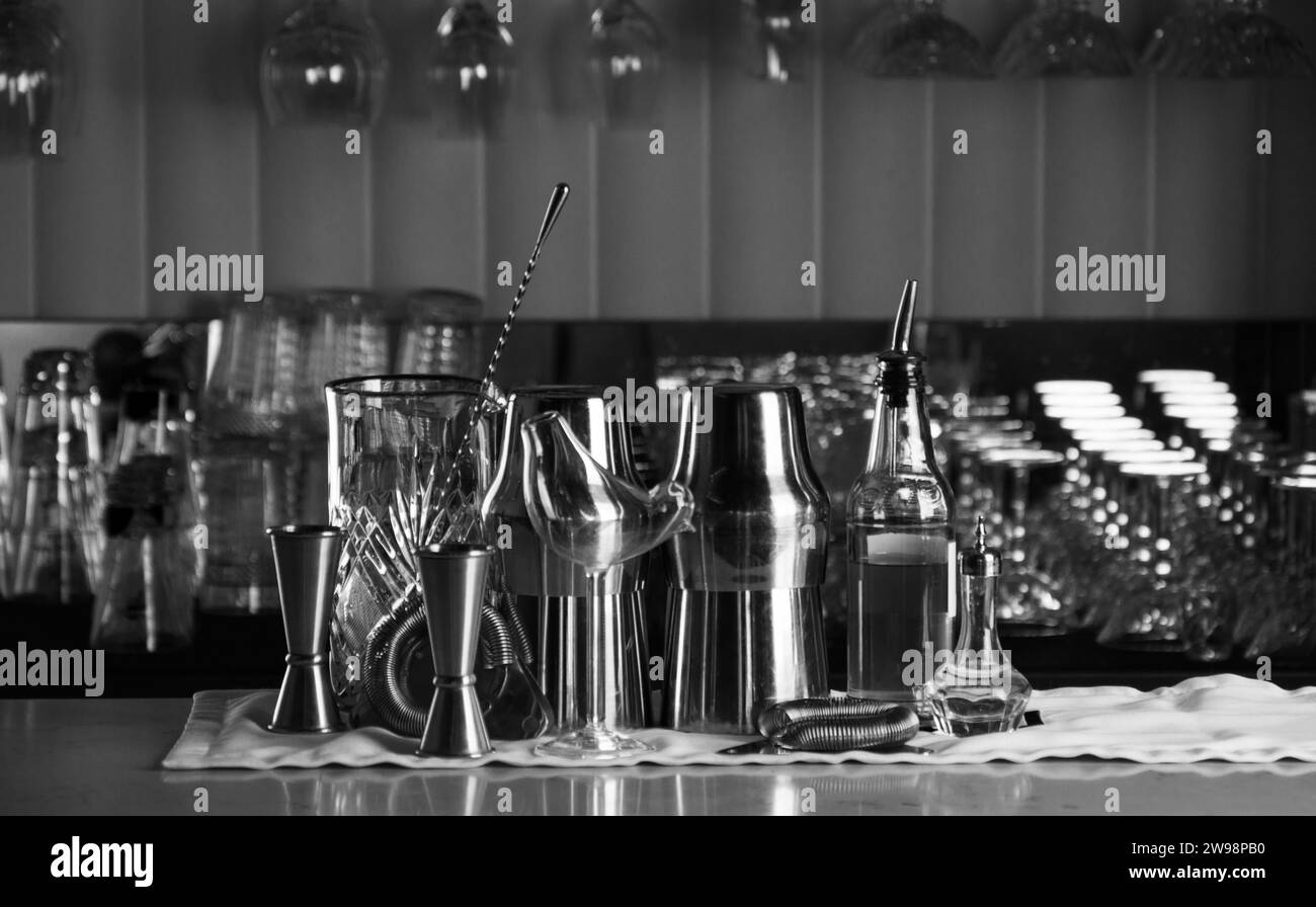 Set di accessori bar per preparare cocktail, situato al bar, dietro c'è una scaffalatura con liquori e alcol forte. Supporti misti Foto Stock