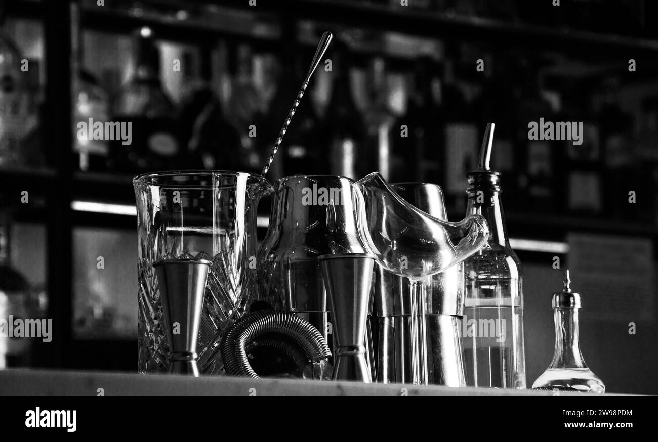 Set di accessori bar per preparare cocktail, situato al bar, dietro c'è una scaffalatura con liquori e alcol forte. Supporti misti Foto Stock