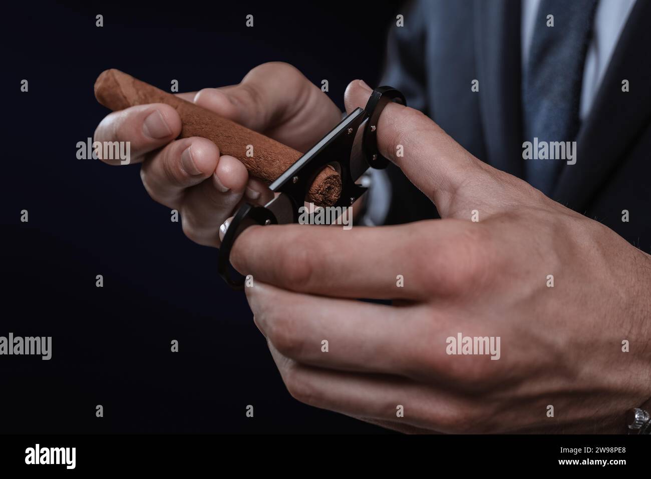 Immagine di mani che tengono una ghigliottina e un sigaro. Concetto di cigar club. Supporti misti Foto Stock