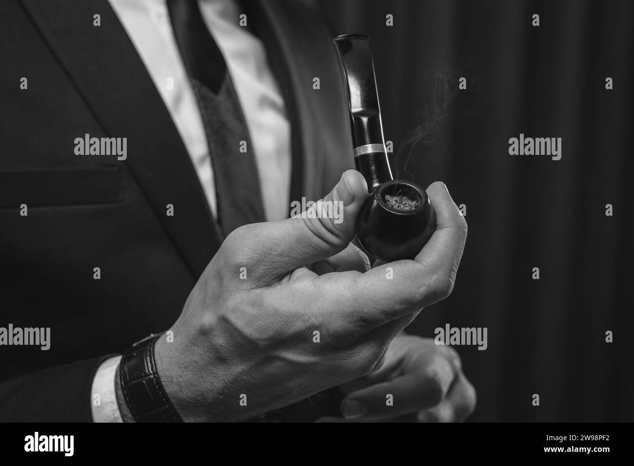 Immagine di mani maschili che tengono un tubo fumante. Concetto di fumo di tabacco. Supporti misti Foto Stock