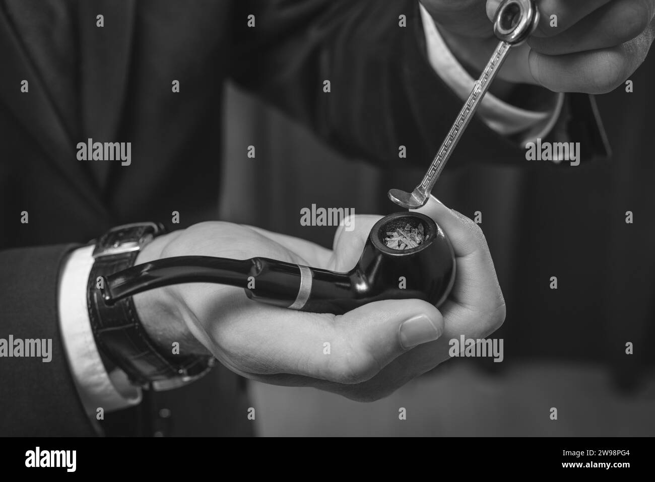 Immagine di mani maschili che tengono un tubo fumante e manomettono. Concetto di fumo di tabacco. Supporti misti Foto Stock