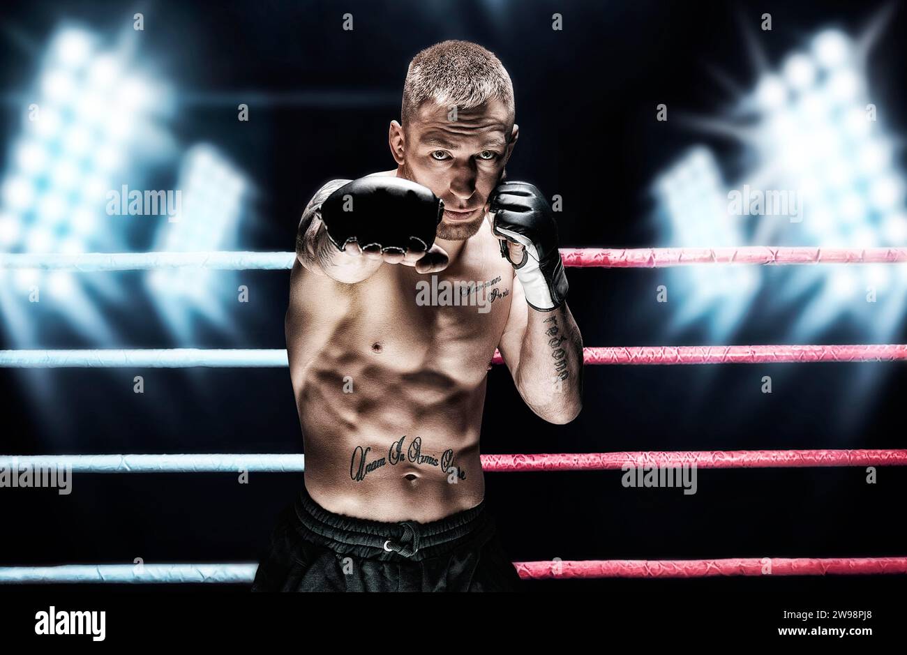 Artista marziale misto che posa sul ring contro i riflettori. Concetto di mma, ufc, boxe tailandese, boxe classica. Supporti misti Foto Stock