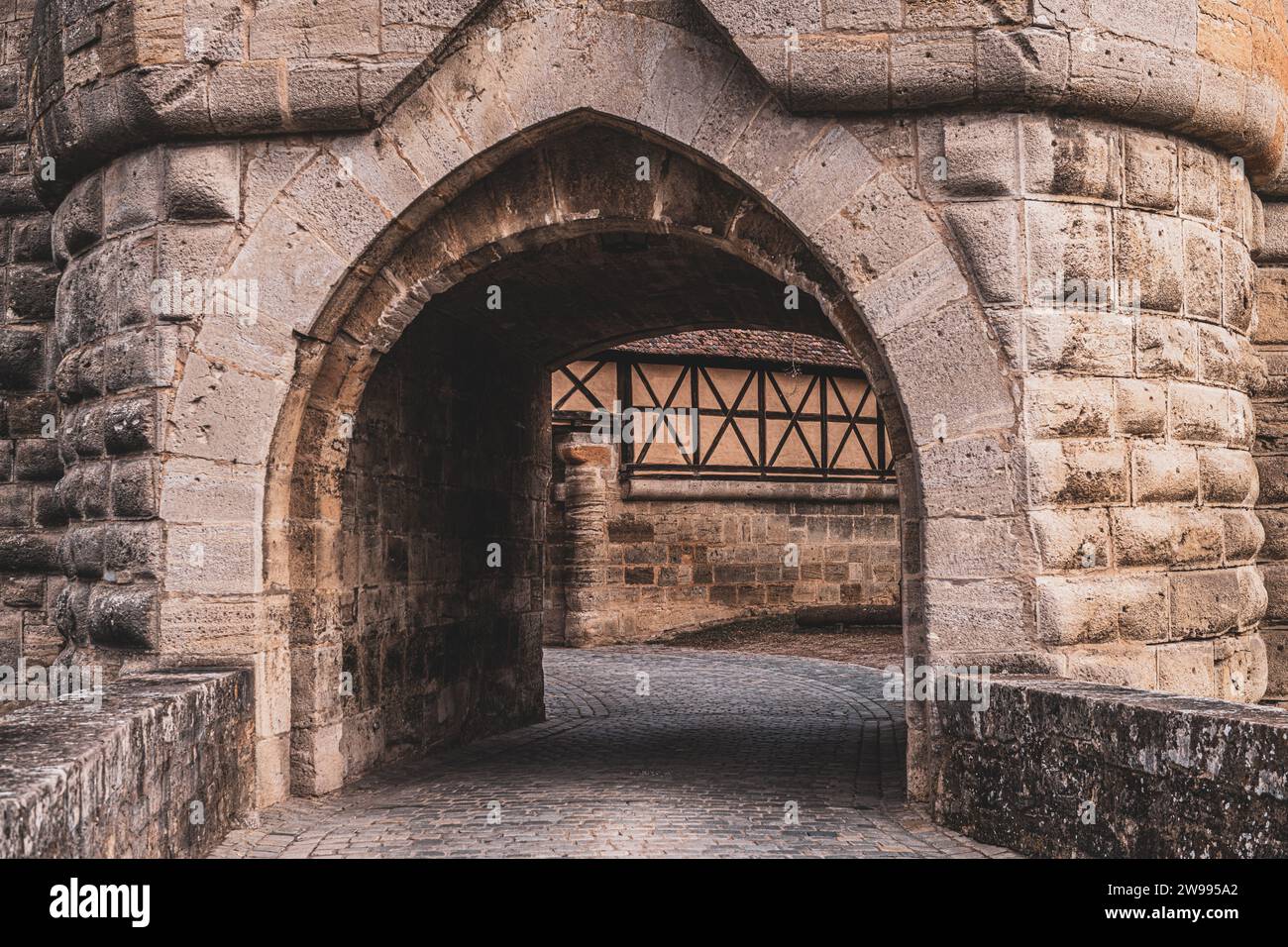 Una strada acciottolata con un arco in pietra in un edificio medievale Foto Stock