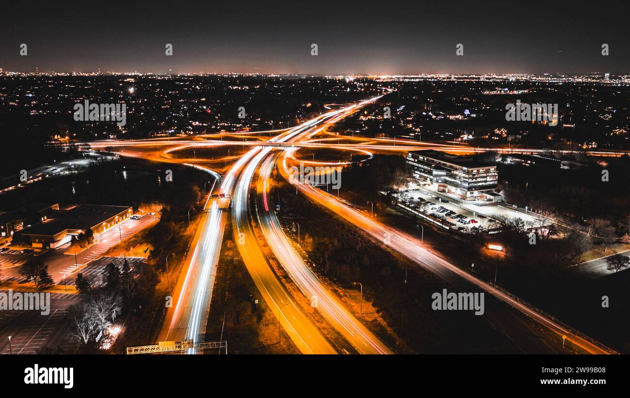 Un tratto di autostrada illuminato di notte, illuminato da lampioni stradali e fari per auto, con alcuni veicoli che viaggiano lungo la strada Foto Stock