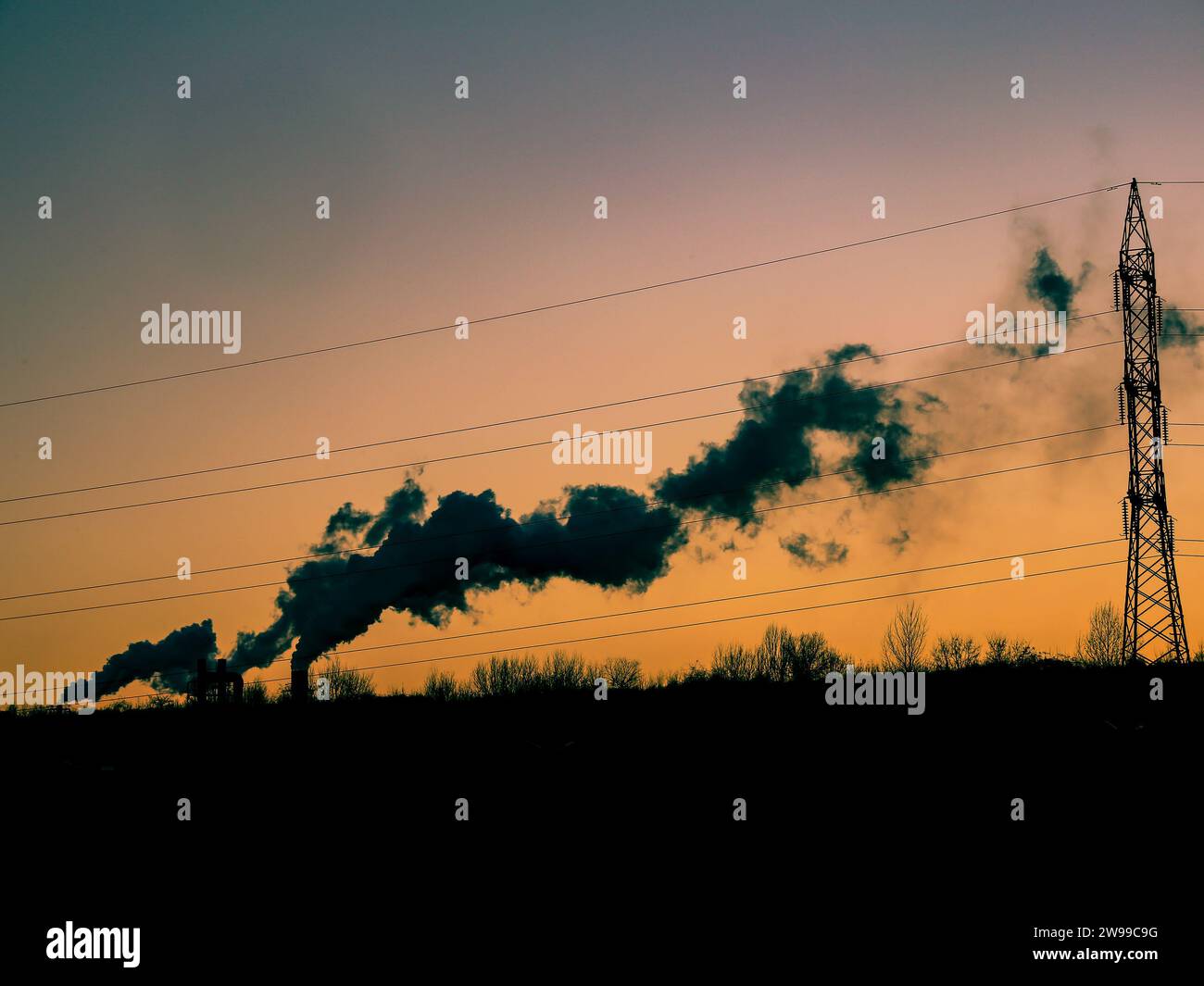 Vista aerea degli alti tubi della centrale a carbone con fumo nero che si muove verso l'alto l'atmosfera inquinante al tramonto. Foto Stock