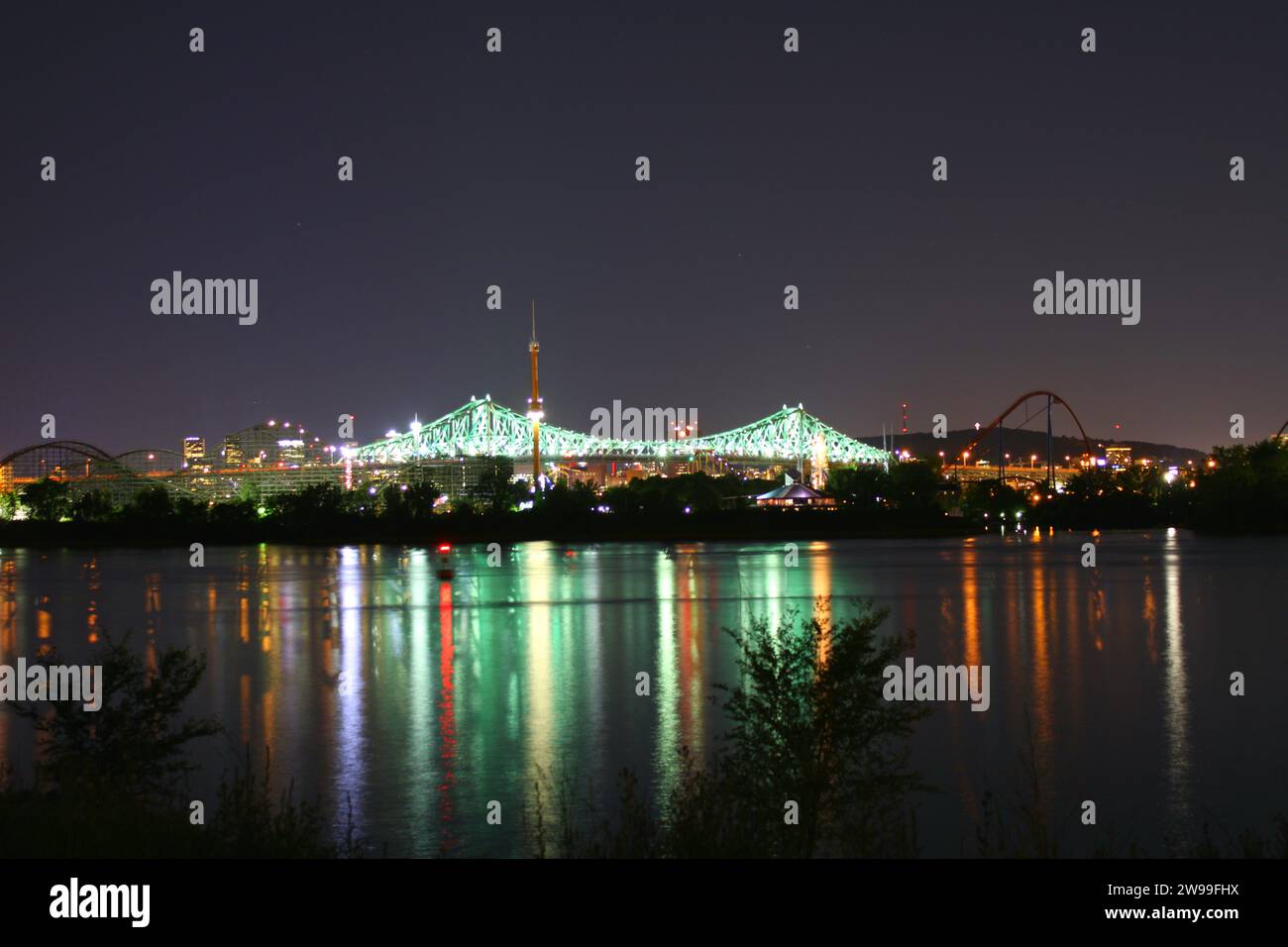 Uno skyline illuminato della città di notte, con le luci luminose che si riflettono sulle acque di un fiume sottostante Foto Stock