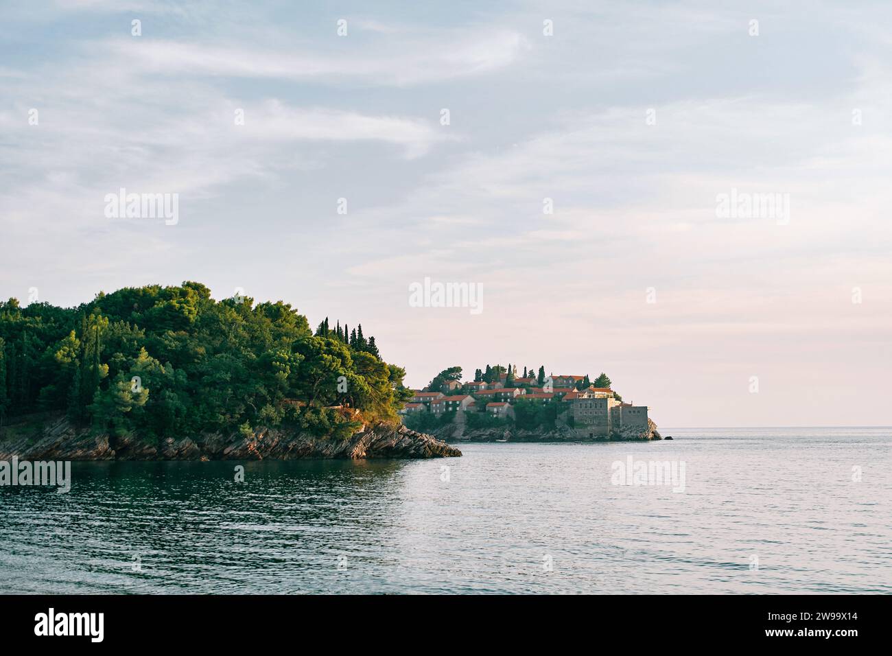 Vista da dietro una verdeggiante sporgenza costiera sull'isola di Sveti Stefan nella baia di Cattaro. Montenegro Foto Stock