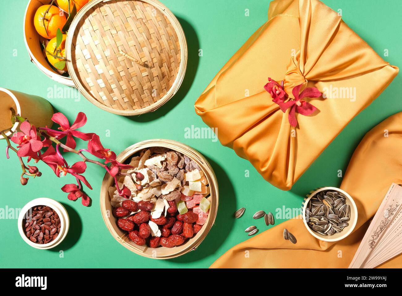 La vaporiera di bambù contiene mandarini, marmellata, giuggiole e caramelle gommose. I semi di melone e i semi di girasole sono conservati in piccole ciotole, in una confezione regalo e in un vaso di flo Foto Stock