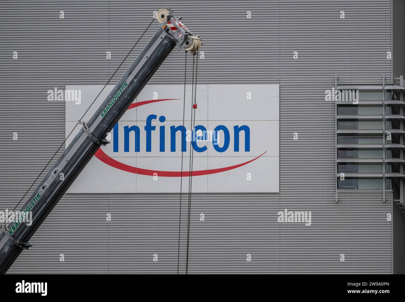 Dresda, Germania. 12 dicembre 2023. Una gru si trova di fronte al logo del produttore del chip sul cantiere per la nuova Smart Power Fab di Infineon. Con la costruzione, Infineon vuole rafforzare la propria base di produzione di semiconduttori che promuovono la decarbonizzazione e la digitalizzazione. (A dpa "New Momentum: Saxon high-tech Sector Optimistic for 2024") credito: Robert Michael/dpa/Alamy Live News Foto Stock