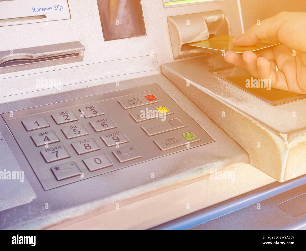Mano femminile che inserisce una carta bancomat nel bancomat per prelevare denaro Foto Stock