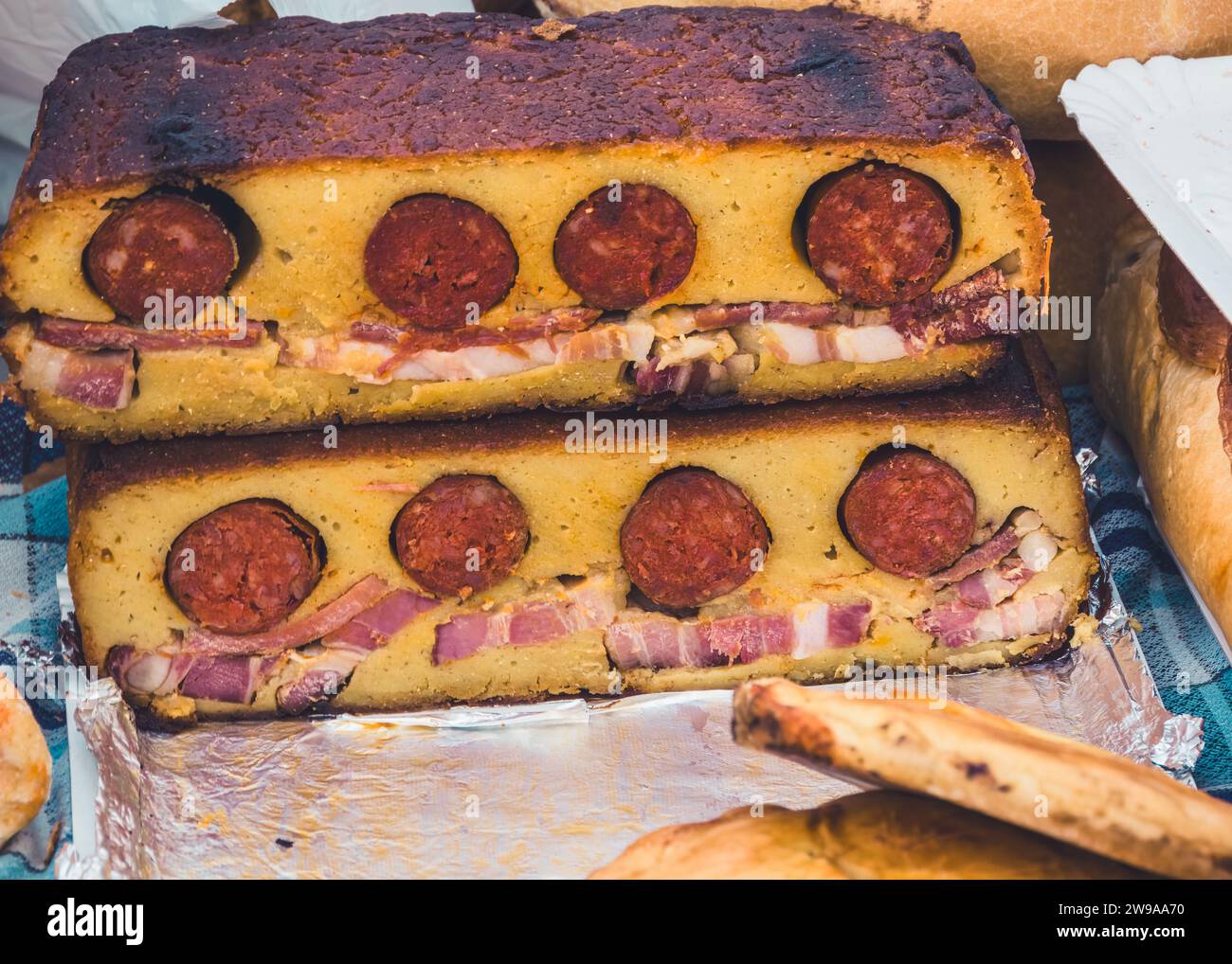 Delizie salate: Pane di mais artigianale con salsiccia e pancetta ('Boroña') al mercato domenicale di Cangas de Onis (Asturias, Spagna) Foto Stock