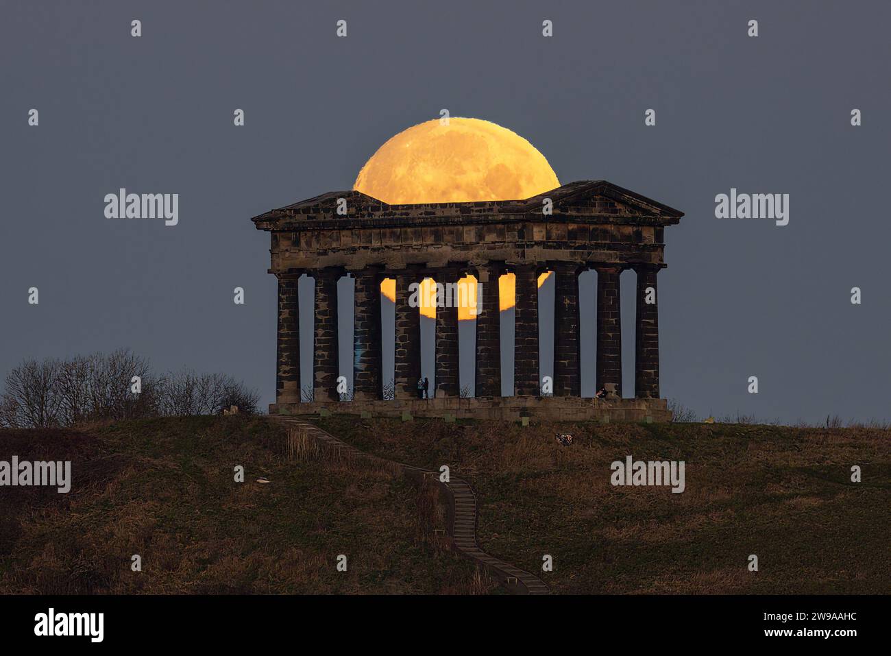 La gente guarda come la Full Cold Moon tramonta al Penshaw Monument, vicino a Washington e Houghton-le-Spring, Regno Unito. 26 dicembre 2023. (Foto di Mark Cosgrove/News Images) in Near Washington and Houghton-le-Spring, Regno Unito il 26/12/2023. (Foto di Mark Cosgrove/News Images/Sipa USA) credito: SIPA USA/Alamy Live News Foto Stock