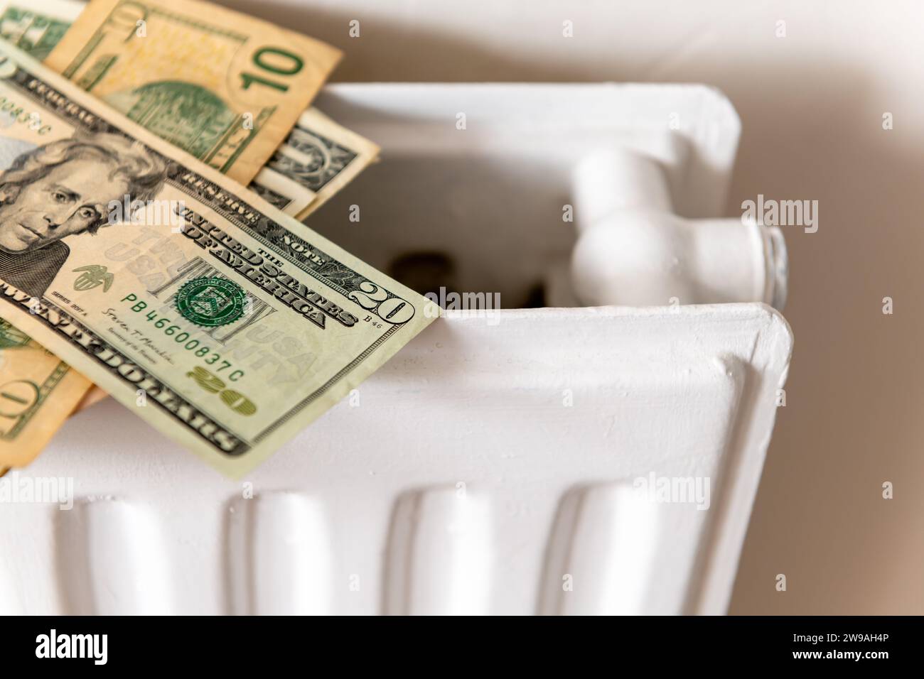 Un mucchio di dollari americani su un radiatore per riscaldamento centrale. Un concetto di riscaldamento e di costo energetico. Foto Stock
