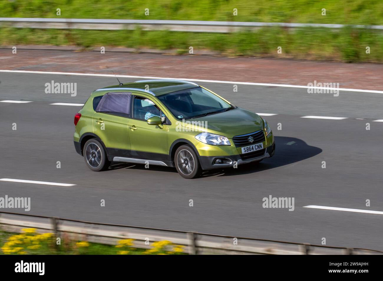 2015 Green Suzuki SX4 SZ-T 1586 cc benzina manuale a 8 velocità, auto subcompatta e crossover, Sport X-Over 4 stagioni; viaggia a velocità sostenuta sull'autostrada M6 a Greater Manchester, Regno Unito Foto Stock