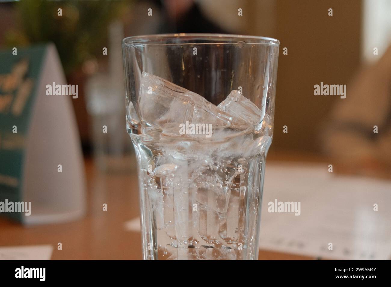 Un tavolo moderno con un bicchiere d'acqua e alcune carte sparse sulla sua superficie Foto Stock