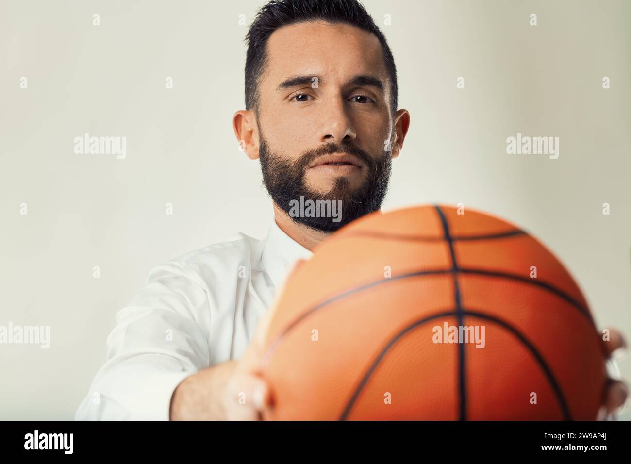 Un professionista d'affari tiene una partita di pallacanestro, illustrando l'intersezione tra sport e strategia aziendale Foto Stock