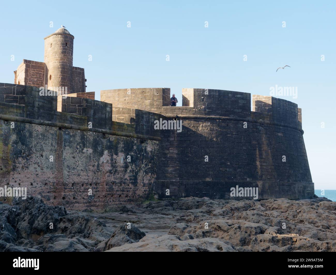 L'uomo si trova alle mura e alla fortezza di Essaouira, in Marocco. 26 dicembre 2023 Foto Stock