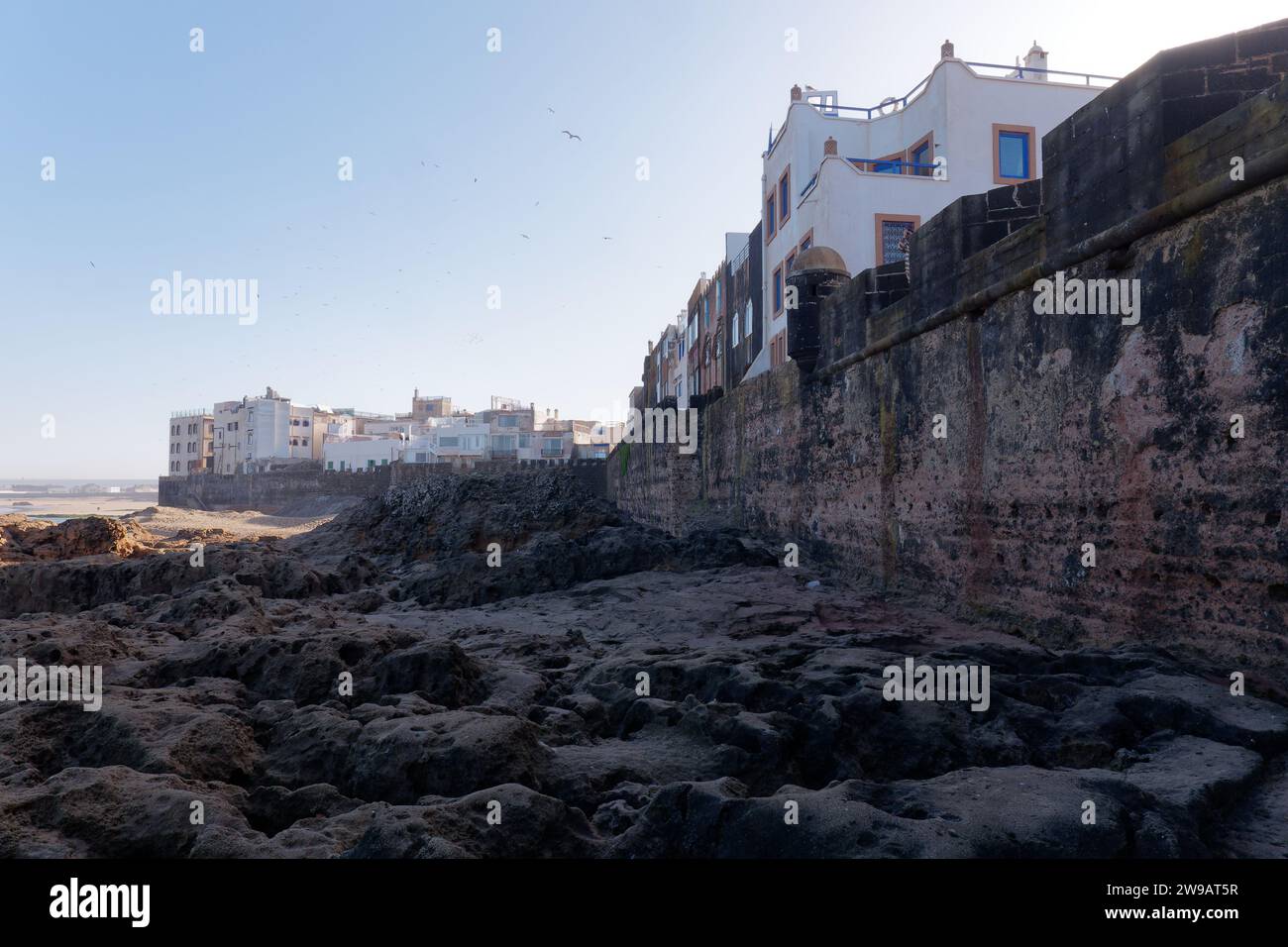 Costa rocciosa oltre le mura della città e la storica Medina con una spiaggia alle spalle a Essaouira, Marocco. 26 dicembre 2023 Foto Stock