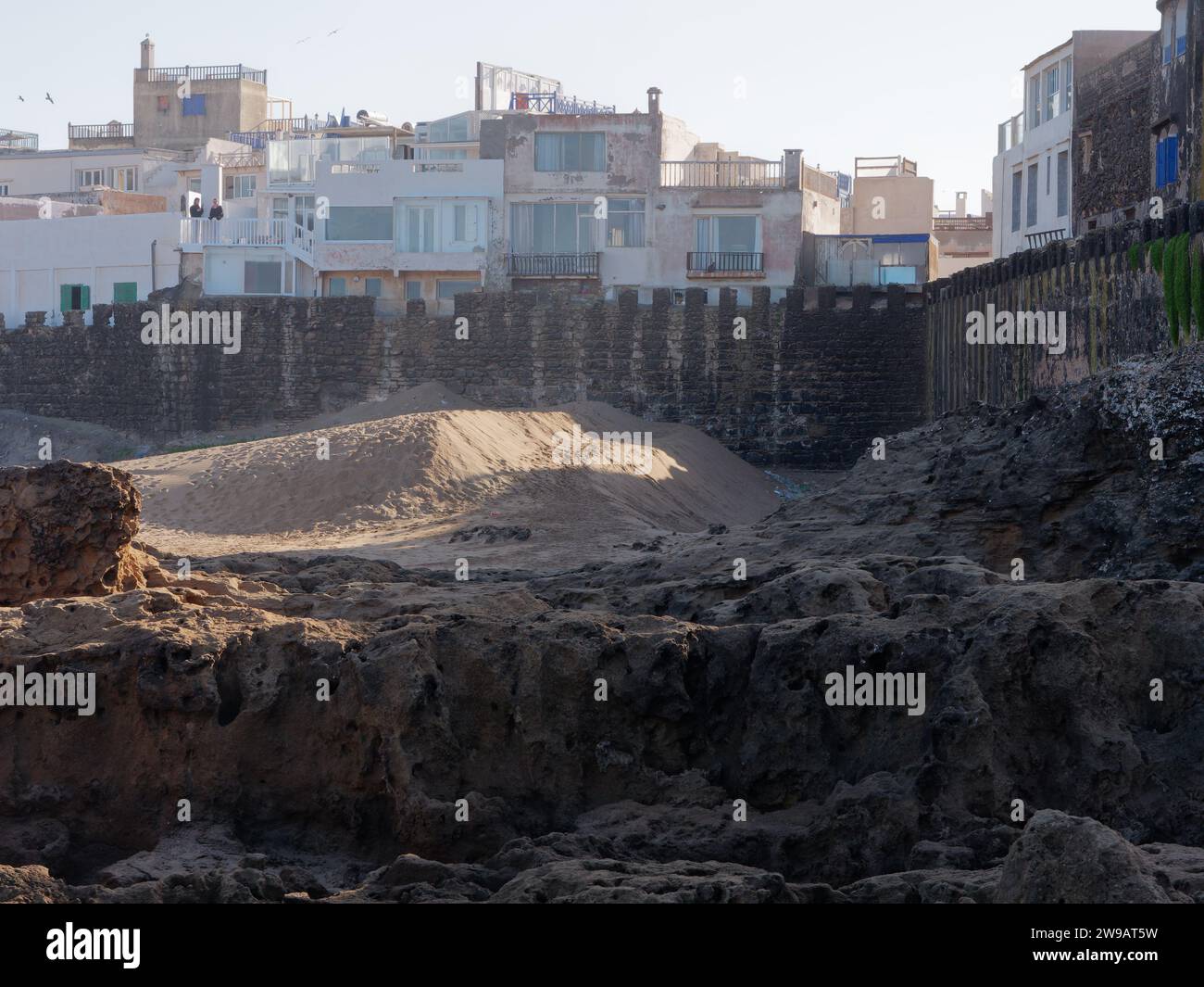 Angolo di una spiaggia sabbiosa con grandi rocce accanto alle mura della città e la storica Medina a Essaouira, Marocco. 26 dicembre 2023 Foto Stock