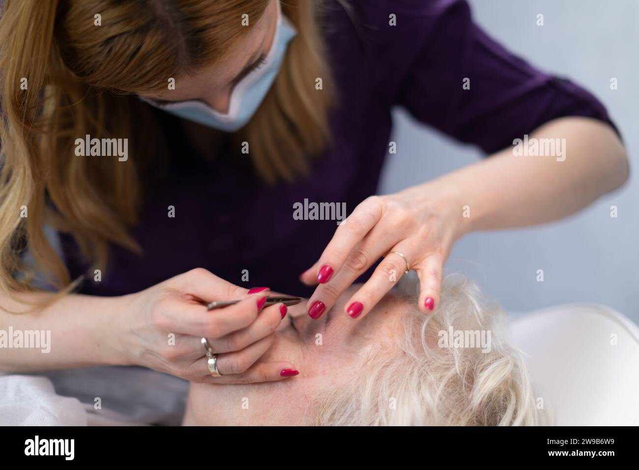 L'estetista rimuove i peli del viso durante la visita del suo cliente. Foto Stock