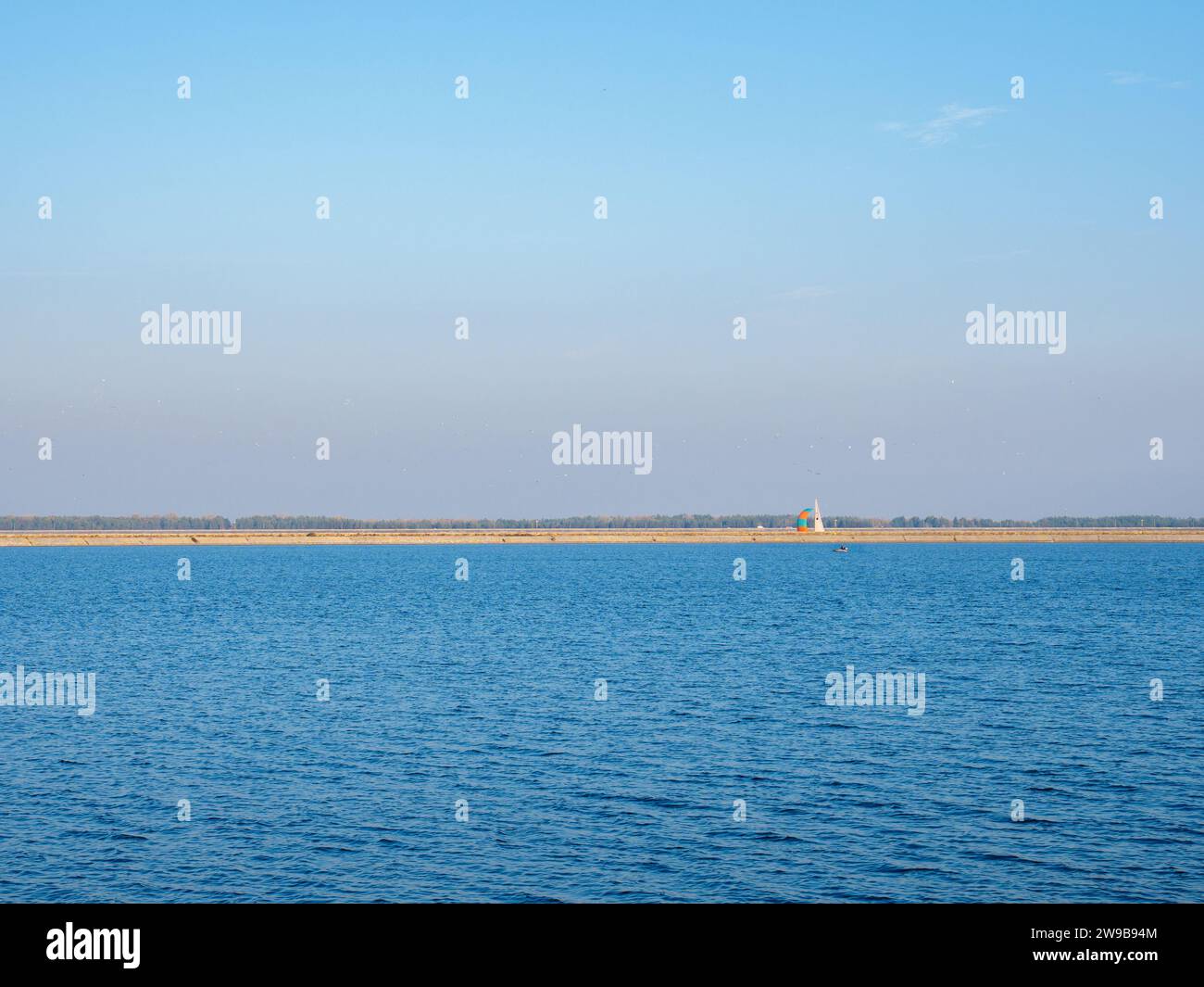 Un grande gregge di uccelli che volano sopra lo sputo del mare di Kiev, acque blu calme con yacht e barca galleggianti, cielo blu e rosa, stretta striscia di sponde all'orizzonte Foto Stock