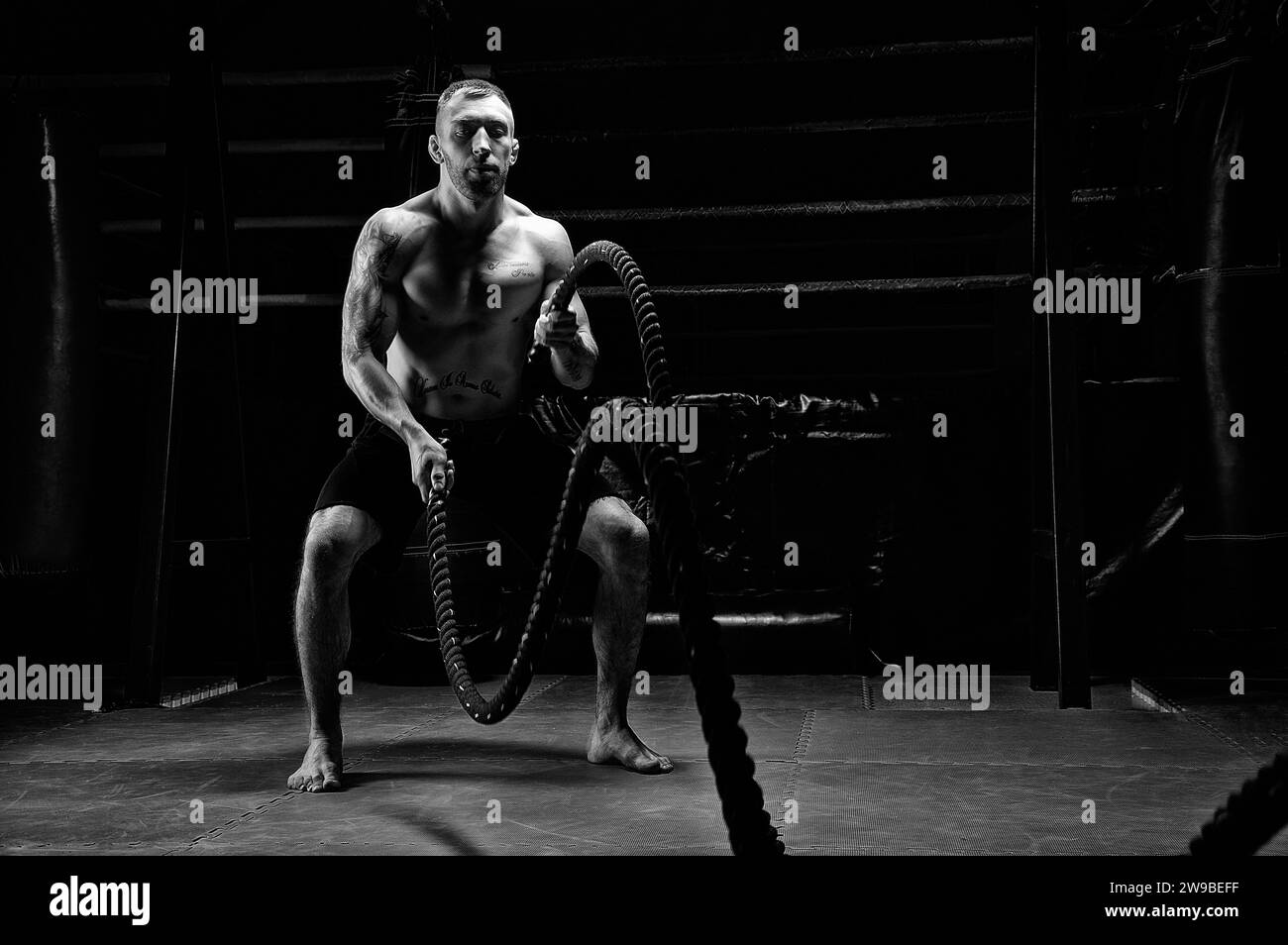 L'atleta lavora con le corde crossfit in palestra. Il concetto di sport, bodybuilding, fitness. Supporti misti Foto Stock