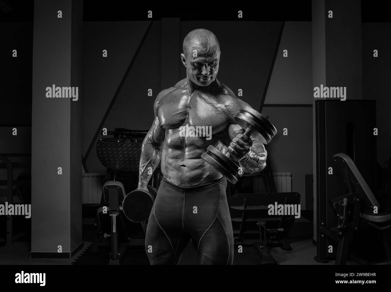 Il sollevatore professionista si sta allenando in palestra. Dumbbell Curl. Concetto di bodybuilding. Supporti misti Foto Stock