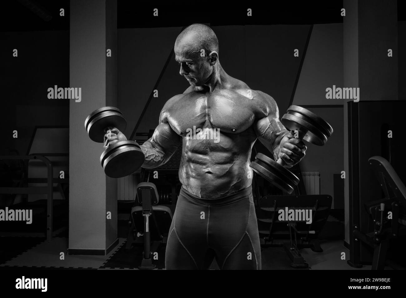 Il sollevatore professionista si sta allenando in palestra. Dumbbell Curl. Concetto di bodybuilding. Supporti misti Foto Stock