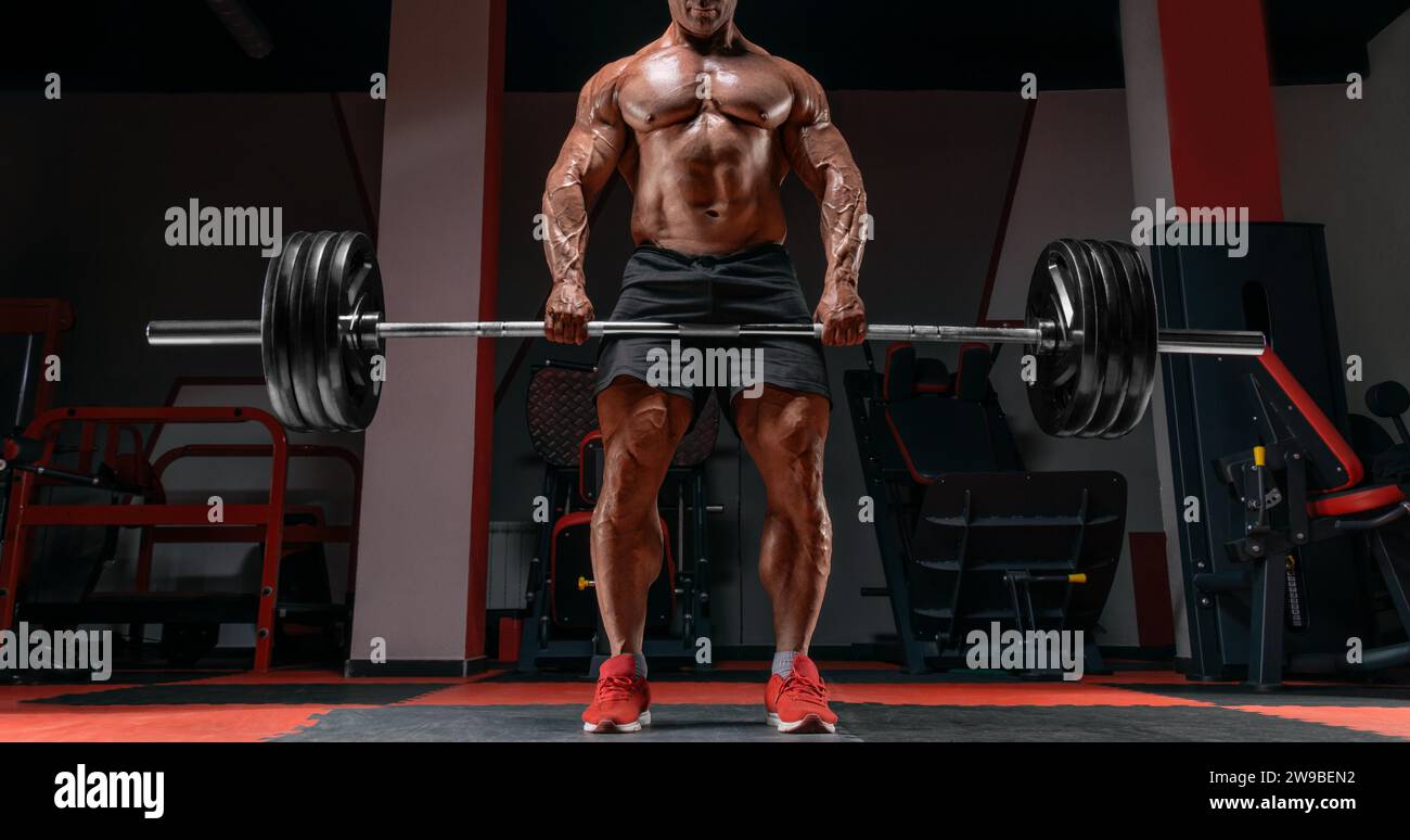 L'uomo muscoloso sta in piedi con un campanello in mano. Deadlift. Concetto di bodybuilding. Supporti misti Foto Stock