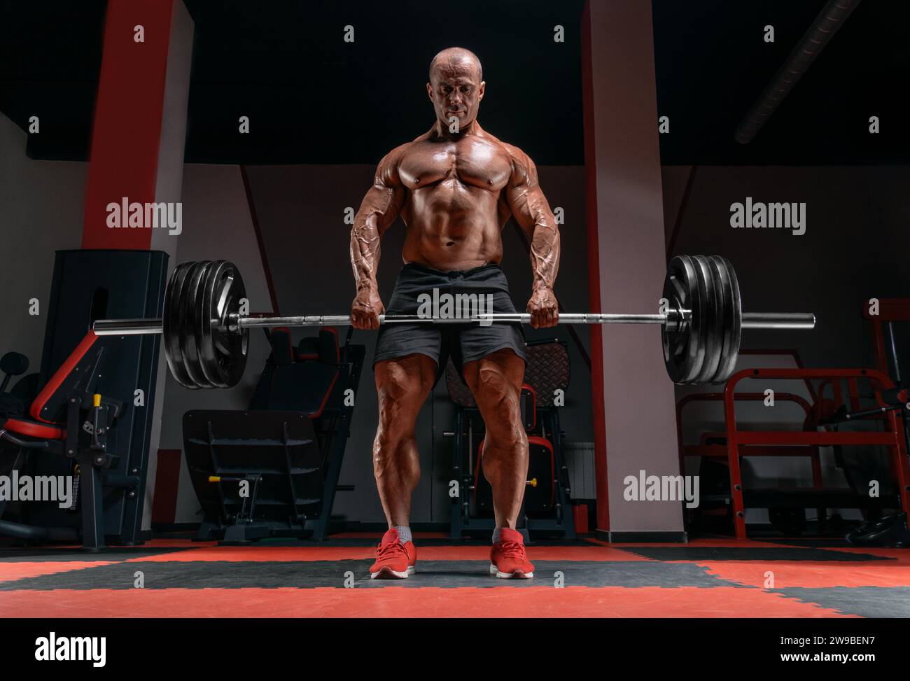L'uomo muscoloso sta in piedi con un campanello in mano. Deadlift. Concetto di bodybuilding. Supporti misti Foto Stock
