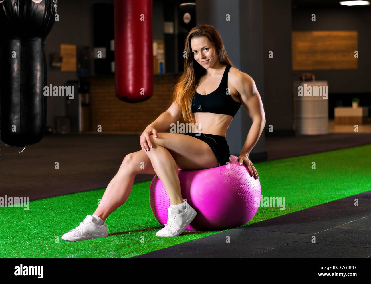 Il campione di bodybuilding si allena in palestra con un'enorme palla rosa. Supporti misti Foto Stock