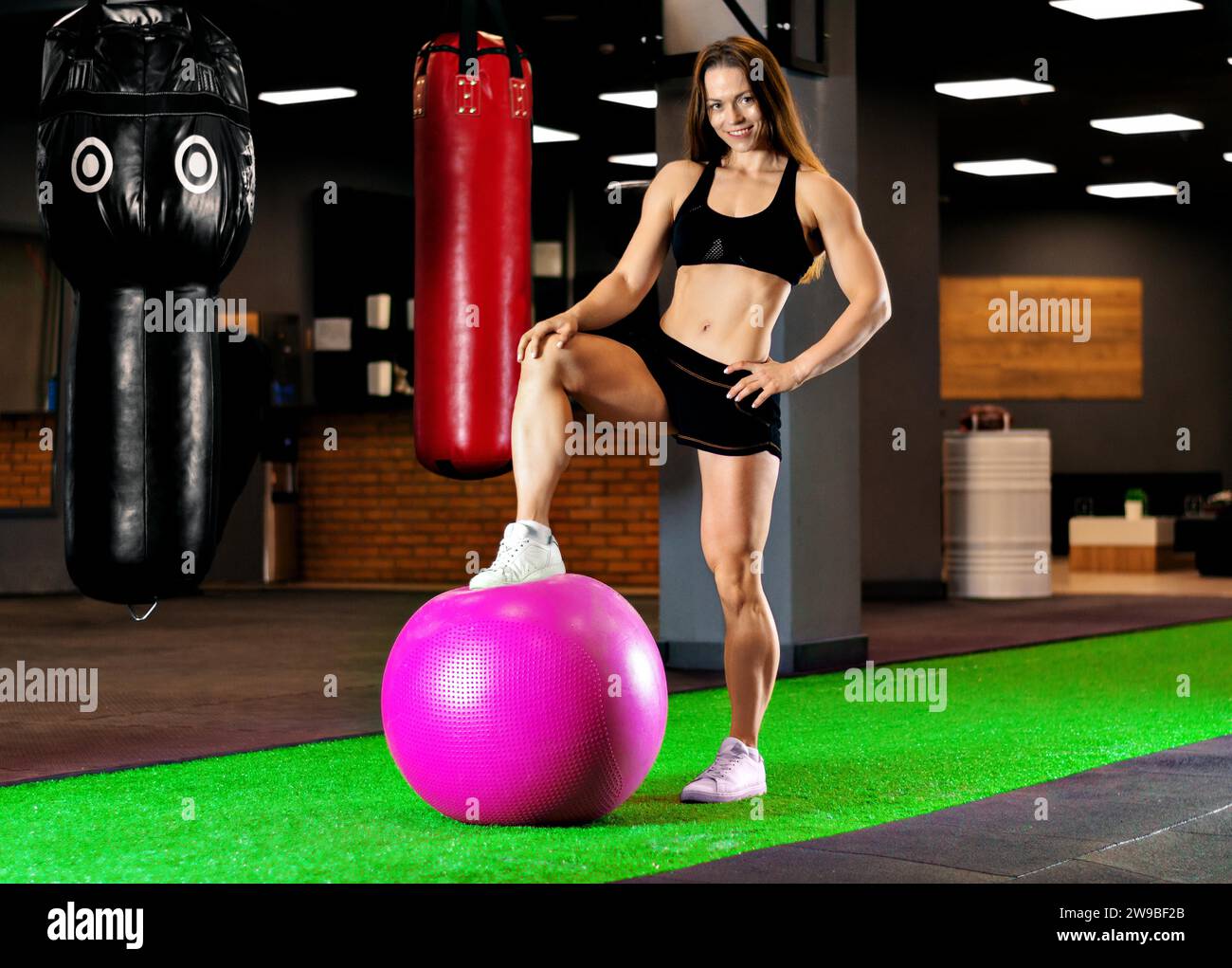 Il campione di bodybuilding si allena in palestra con un'enorme palla rosa. Supporti misti Foto Stock