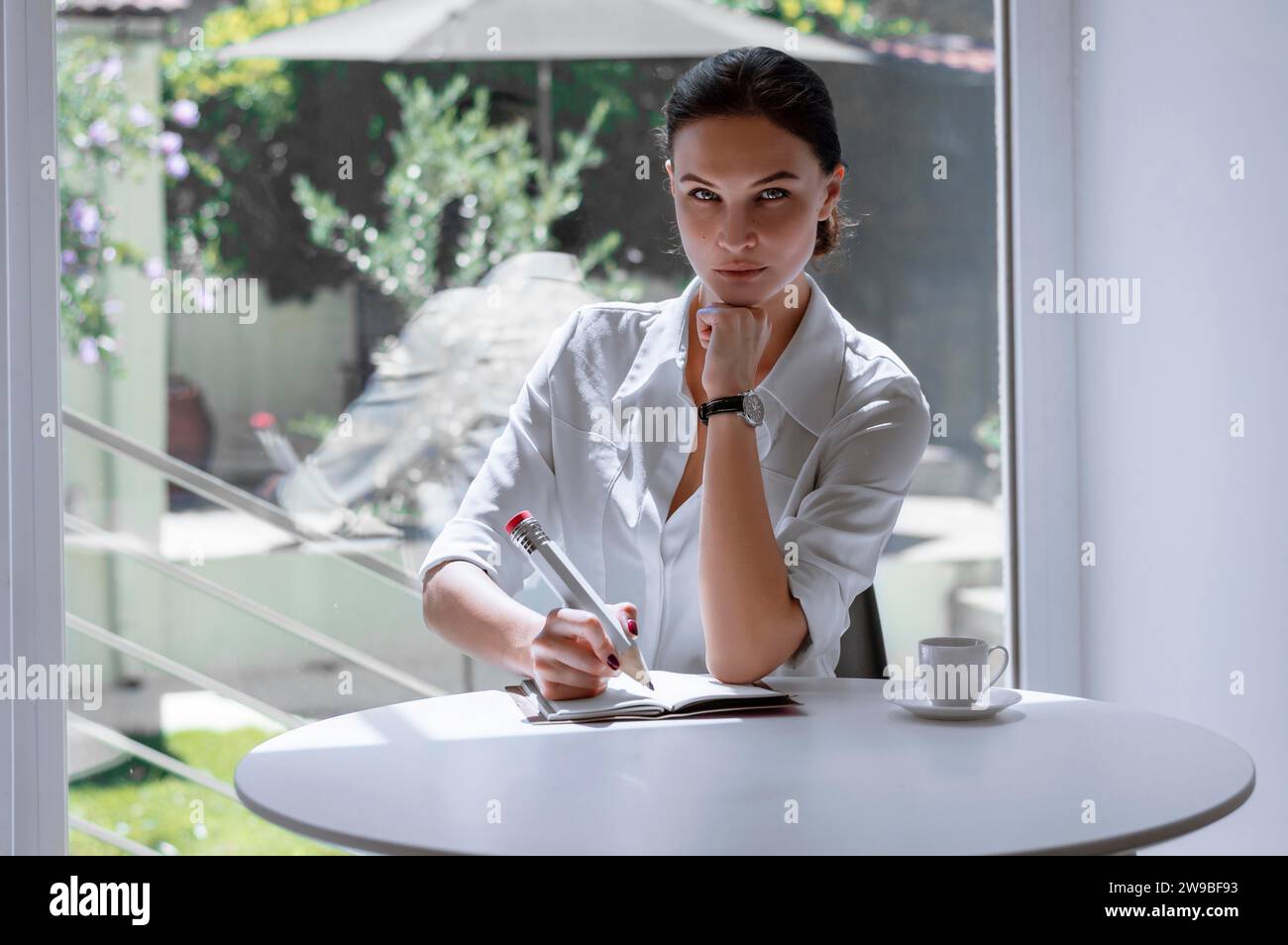 La ragazza scrive in un quaderno con una matita grande. Concetto di colloquio di lavoro, affari, successo. Supporti misti Foto Stock