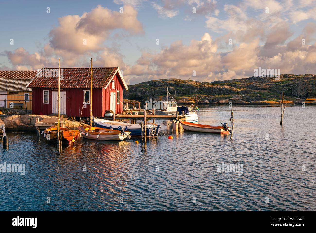 Sorge il sole sulle colorate case di legno nel porto di Björholmen sull'isola di Tjörn, nell'arcipelago della costa occidentale della Svezia Foto Stock