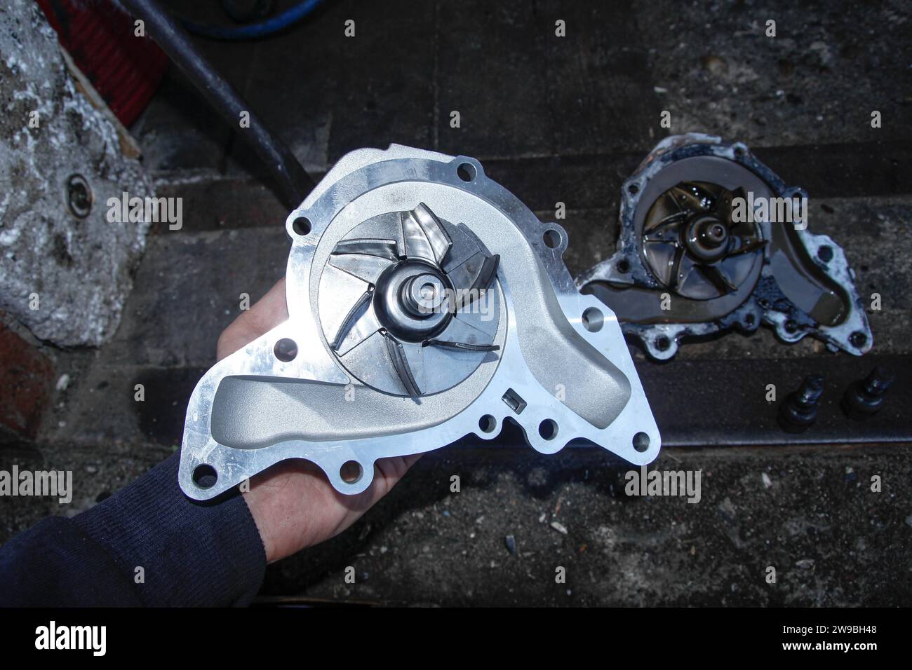 Pompe del sistema di raffreddamento del motore per auto nuove e vecchie, sostituzione della pompa per auto, meccanico, guanto, viti, motore, officina Foto Stock
