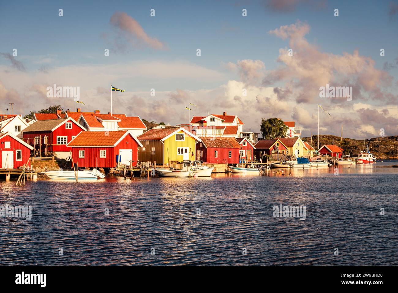 Sorge il sole sulle colorate case di legno nel porto di Björholmen sull'isola di Tjörn, nell'arcipelago della costa occidentale della Svezia Foto Stock