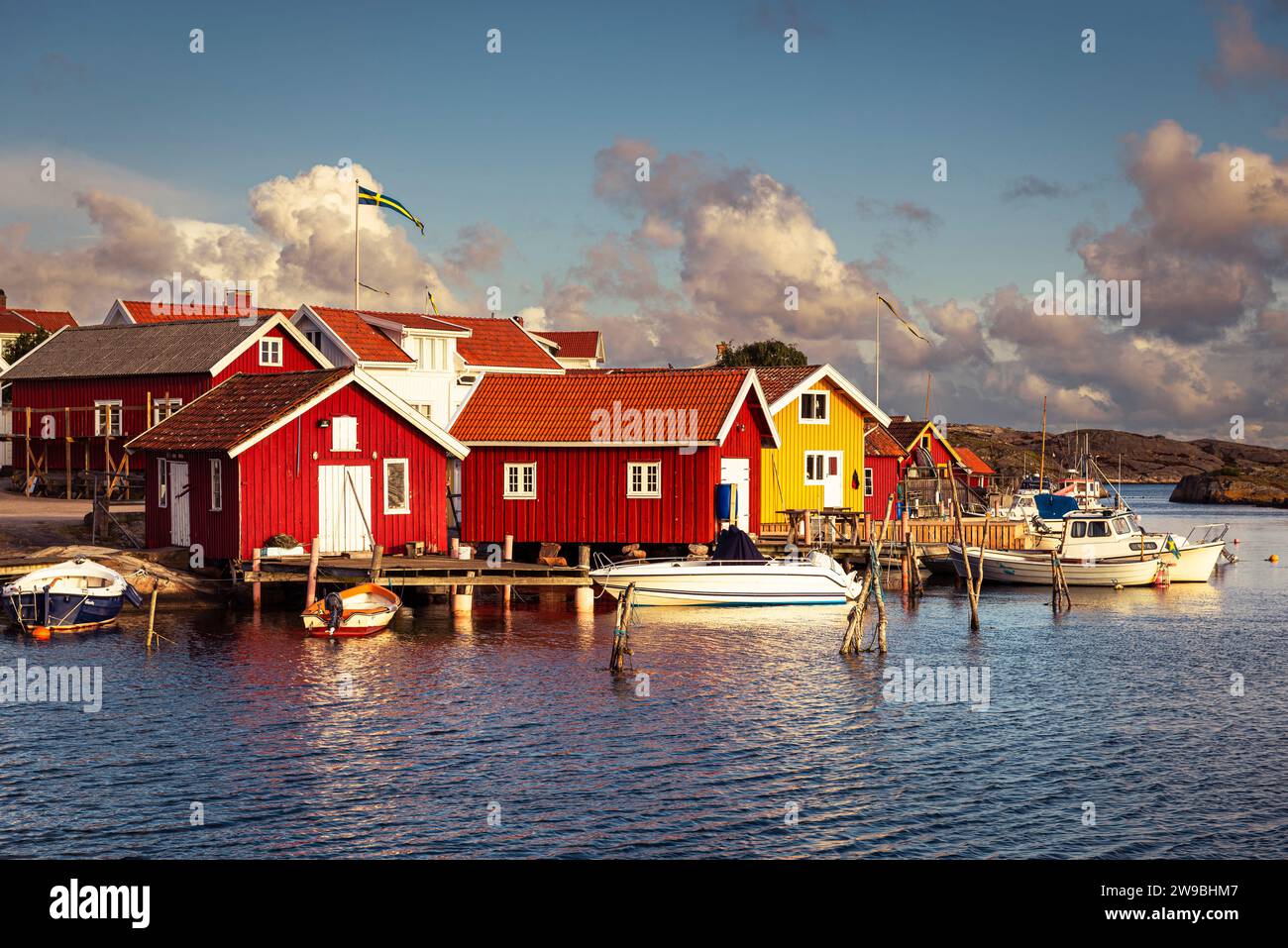 Sorge il sole sulle colorate case di legno nel porto di Björholmen sull'isola di Tjörn, nell'arcipelago della costa occidentale della Svezia Foto Stock