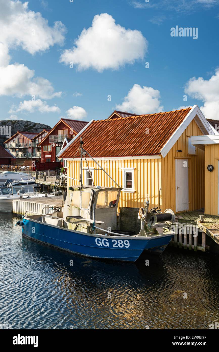 Barche da pesca presso il molo di legno del porto di fronte a una capanna gialla nel porto di Björholmen, nell'arcipelago dell'isola di Tjörn, Bohuslän, Svezia Foto Stock