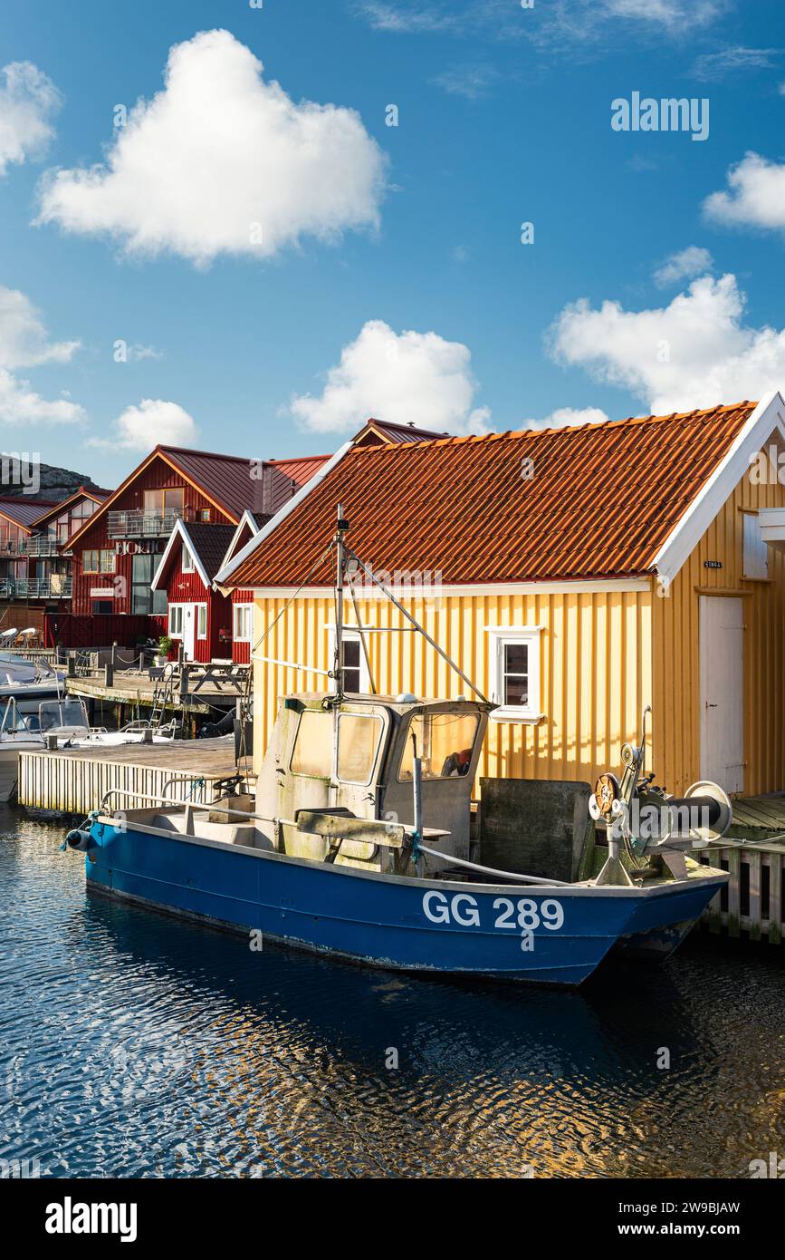 Barche da pesca presso il molo di legno del porto di fronte a una capanna gialla nel porto di Björholmen, nell'arcipelago dell'isola di Tjörn, Bohuslän, Svezia Foto Stock