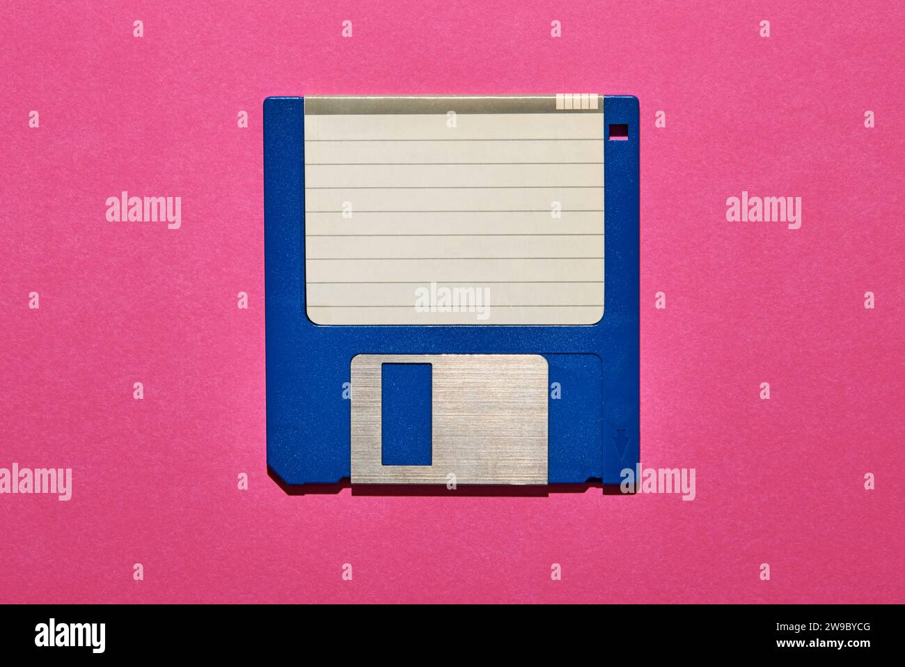 Vista dall'alto della carta bianca con righe attaccate sul disco floppy blu su sfondo rosa Foto Stock