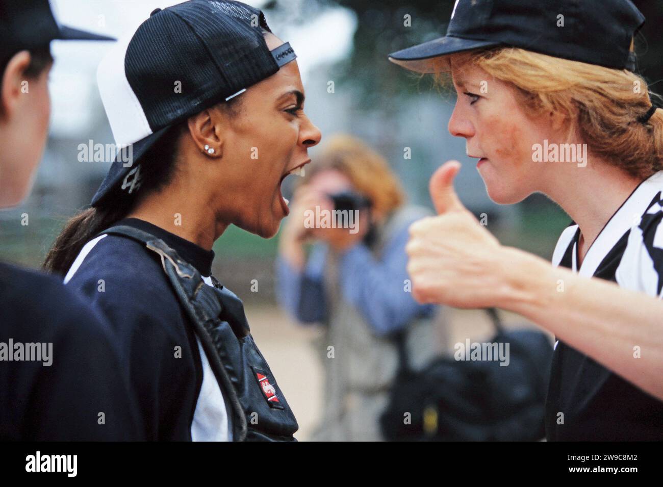 Un impero femminile e un ricevitore che urlano l'uno contro l'altro durante una partita di baseball Foto Stock