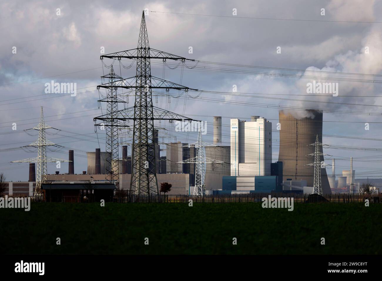 Impression vom RWE-Kraftwerk Bergheim Niederaußem. DAS Kohlekraftwerk zieht seine Schwaden in Die kalte Winterluft. In der Umgebung glänzen Strommasten, Windräder und Wolkenformationen in der kalten Wintersonne. Stadtwerke geben bekannt: Strompreise steigen für Privathaushalte 2024 um 32 Prozent. Grund ist eine Entscheidung der Bundesregierung, Gelder in Höhe von 5,5 Milliarden zur Stabilisierung der Netzentgelte zu streichen. Themenbild, Symbolbild. Bergheim, 26.12.2023 NRW Deutschland *** impressione della centrale elettrica RWEs Bergheim Niederaussem la centrale elettrica a carbone affonda nel col Foto Stock