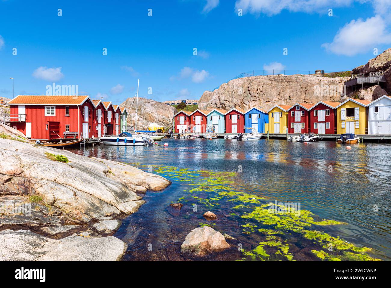 Capannoni per barche e magazzini con colorate facciate in legno e rocce di granito nel porto di Smögen, nell'arcipelago della costa occidentale svedese Foto Stock