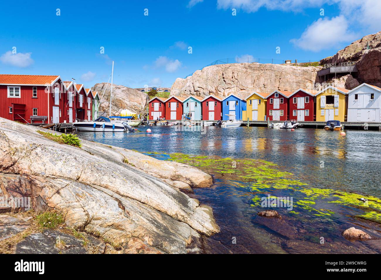 Capannoni per barche e magazzini con colorate facciate in legno e rocce di granito nel porto di Smögen, nell'arcipelago della costa occidentale svedese Foto Stock