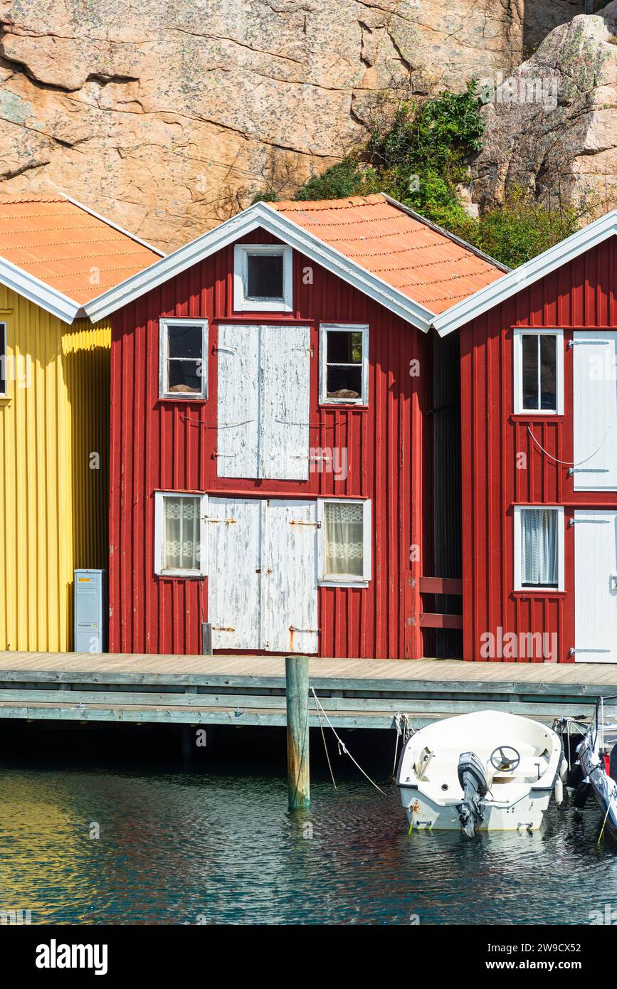 Magazzino con facciata in legno rosso davanti a rocce di granito sul lungomare del porto di Smögen, nell'arcipelago della costa occidentale svedese Foto Stock
